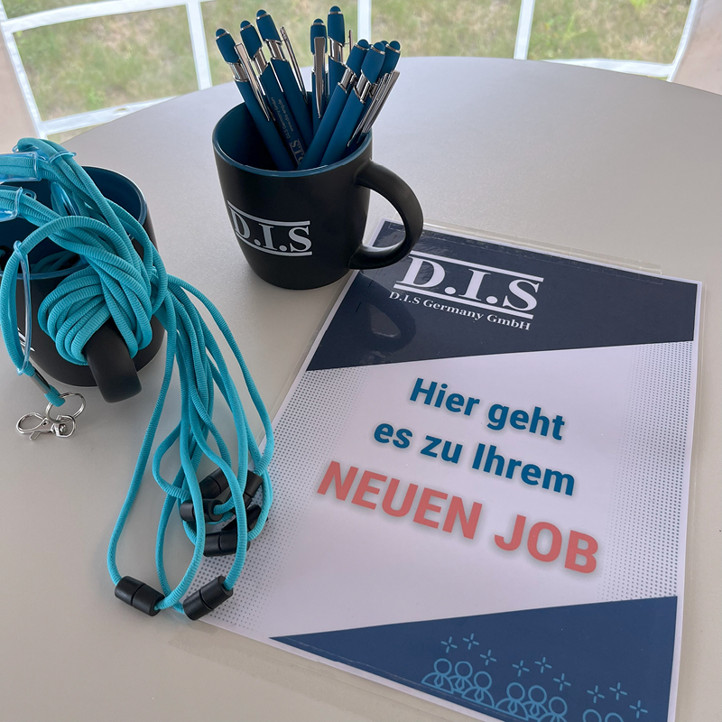 Ein Tisch mit blauem Schreibwaren, einem Becher und einem Schild für Jobangebote.