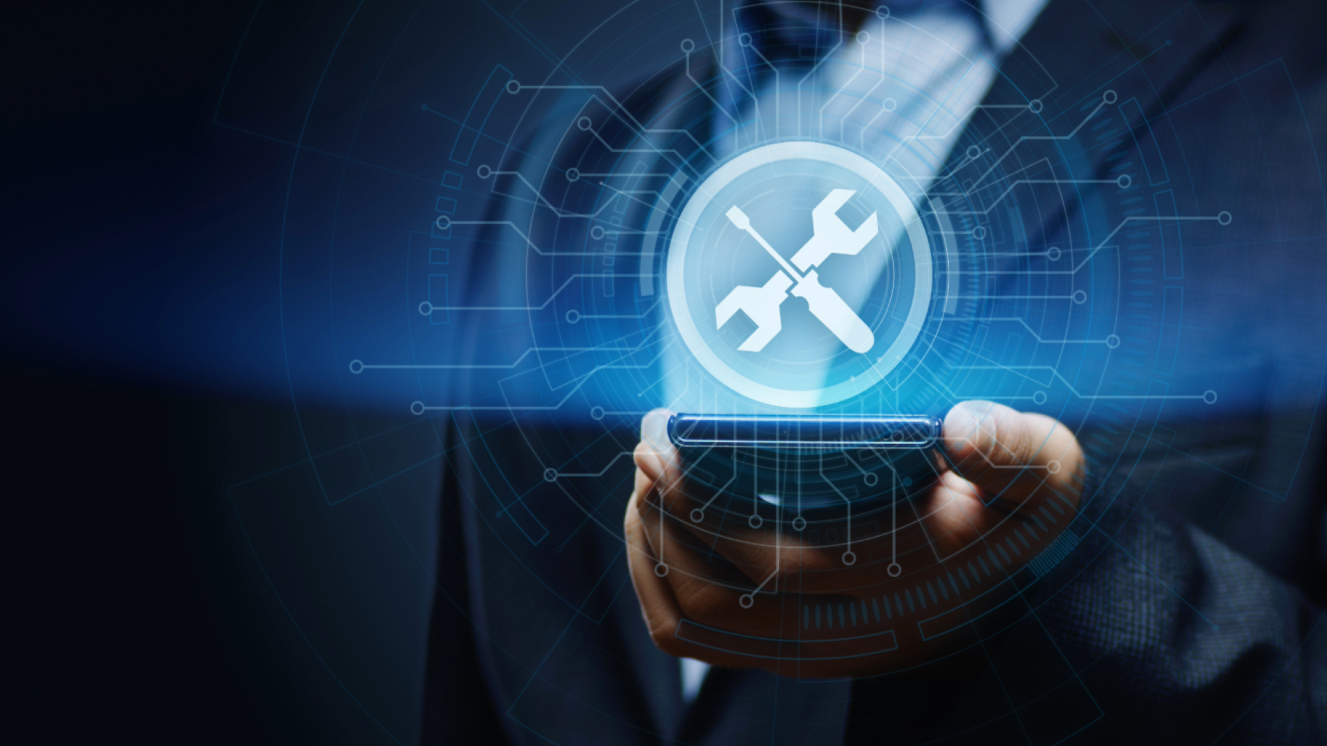 Eine Person im Anzug hält ein Smartphone mit schwebendem Technik-Symbol.