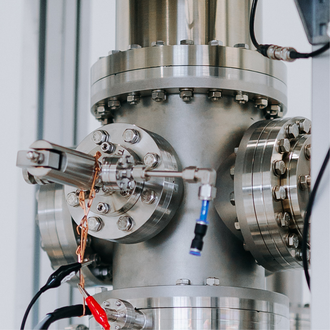 Ein silbernes, zylindrisches Metallgerät mit Schrauben und blauen Kabeln